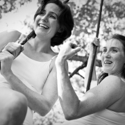 photo of the founders of NECCA sitting on a trapeze outside in the summertime